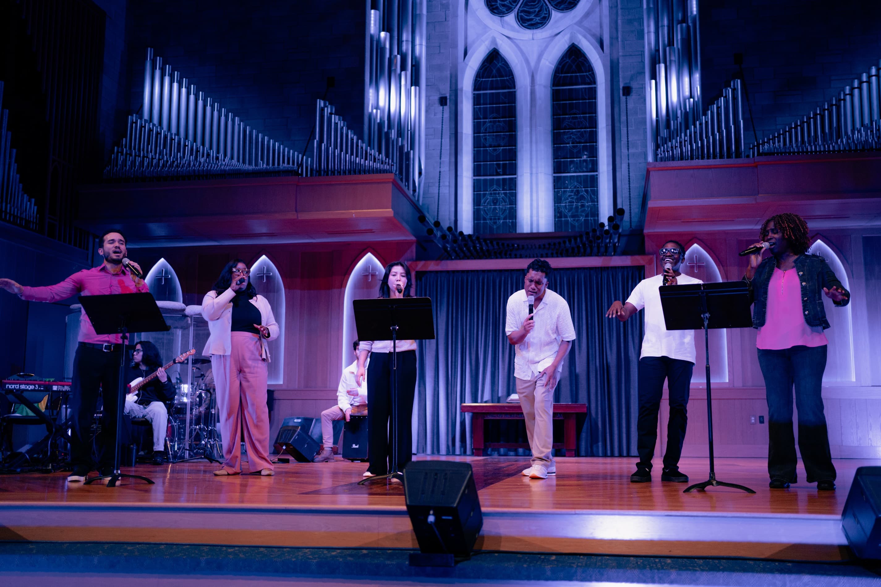 Vocalists on stage with pipe organ lighting